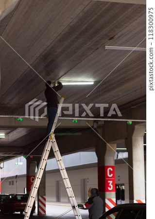 City Worker electrician repairs LCD lamp on mall parking. City Worker electrician repairs LCD lamp on mall parking. 118300975