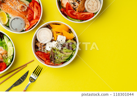 Top view of fresh poke bowls on yellow background 118301044