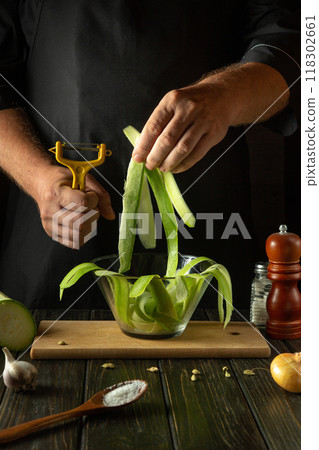 Chef prepares sliced zucchini before stir frying with vegetables in the kitchen. Vegetable marrow cooking concept for healthy vegetarian diet Chef prepares sliced zucchini before stir frying with vegetables in the kitchen. Vegetable marrow cooking concept for healthy vegetarian diet 118302661