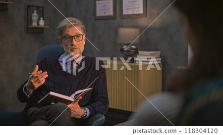 Mature psychotherapist takes notes in notebook, communicates with patient 118304120