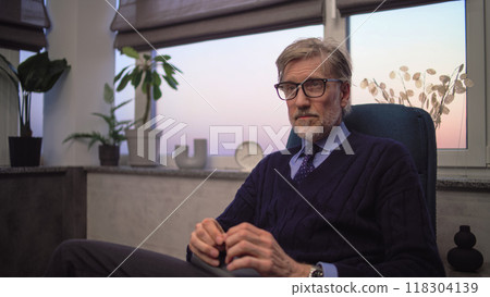 Professional psychologist sits in chair, listens to patient and asks questions during therapy 118304139