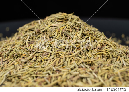 Pile of chopped dry rosemary seasoning on a black background. 118304750