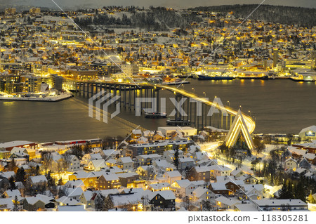 Panorama of Norwegian city of Tromso in the winter. Snowy roofs, bridge, embankment near the port and fishing ships. Evening lights Panorama of Norwegian city of Tromso in the winter. Snowy roofs, bridge, embankment near the port and fishing ships. Evening lights 118305281
