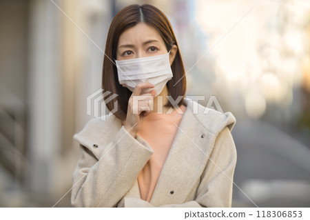 Middle-aged woman walking outdoors wearing a mask Middle-aged woman walking outdoors wearing a mask 118306853