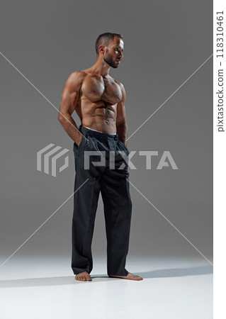 Chic and powerful. Image of young athletic man in loose, dark trousers, showing perfect blend of athleticism and casual style. Chic and powerful. Image of young athletic man in loose, dark trousers, showing perfect blend of athleticism and casual style. 118310461