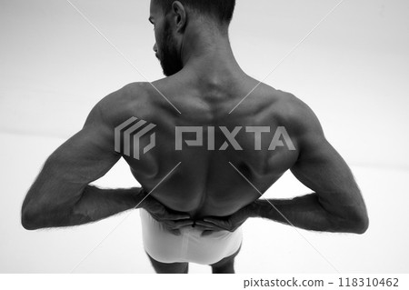 Young handsome man with toned body posing in underwear holding hands on lower back. Photo in monochrome filter. 118310462
