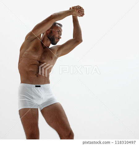 Dynamic shot of man's side profile, with his arm stretched out and muscles flexed. Intense gaze and sculpted body. Dynamic shot of man's side profile, with his arm stretched out and muscles flexed. Intense gaze and sculpted body. 118310497