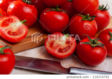 Red tomatoes and knife on wooden cutting board 118310782