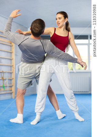 Young girl practicing self-defense techniques in pair with middle-aged man 118310988