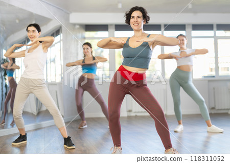 Hispanic woman learning modern street dancing during group class 118311052