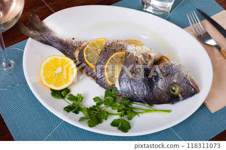 Top view of whole grilled dorada served with lemon and greens at plate Top view of whole grilled dorada served with lemon and greens at plate 118311073