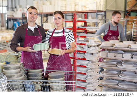 Artisan pair showcasing handcrafted ceramic plates in workshop 118311074