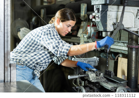 Young woman working on drilling machine in metalworking workshop Young woman working on drilling machine in metalworking workshop 118311112