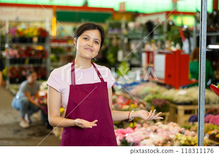 Friendly young Asian saleswoman inviting to colorful flower market 118311176