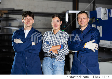 Portrait of two positive workers and girl student in the metalworking workshop of metallurgical plant Portrait of two positive workers and girl student in the metalworking workshop of metallurgical plant 118311183