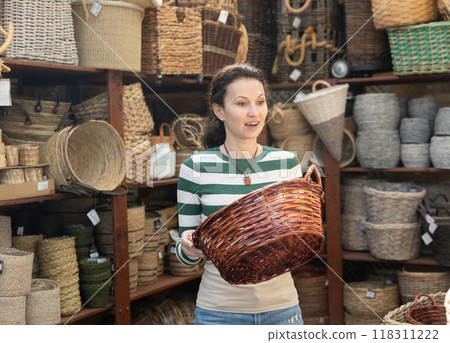 Woman choosing a wicker basket at hardware store Woman choosing a wicker basket at hardware store 118311222