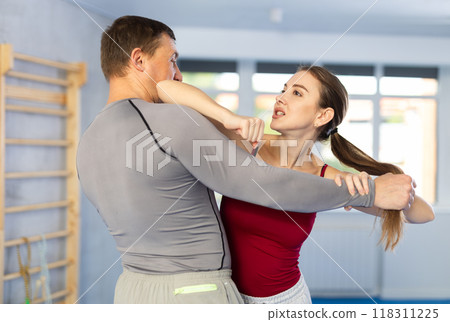 Young girl practicing self-defense techniques in pair with middle-aged man Young girl practicing self-defense techniques in pair with middle-aged man 118311225
