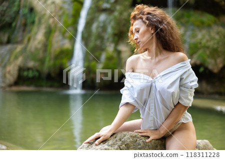 Erotic portrait of a half-naked woman with loose hair against the backdrop of tropical waterfall Erotic portrait of a half-naked woman with loose hair against the backdrop of tropical waterfall 118311228