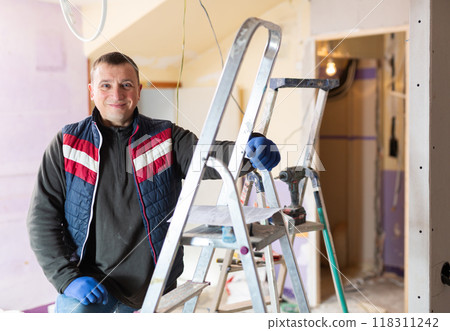 Repair man standing in apartment and looking at camera 118311242