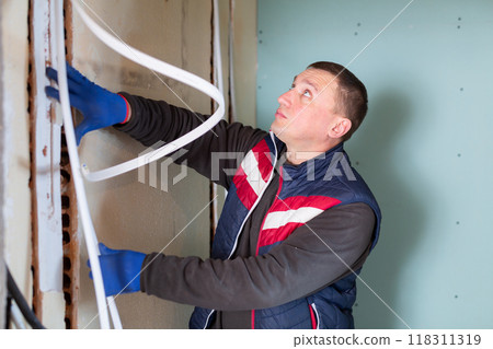 Repair man lying down cable duct in room 118311319