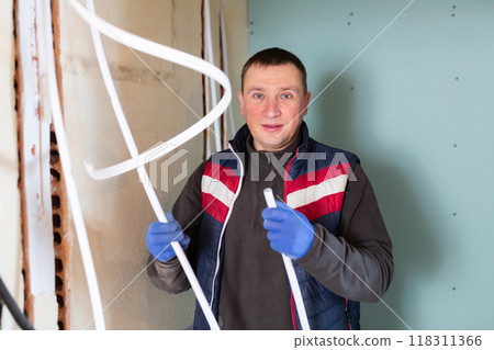 Repair man with cable duct standing in room and looking at camera Repair man with cable duct standing in room and looking at camera 118311366