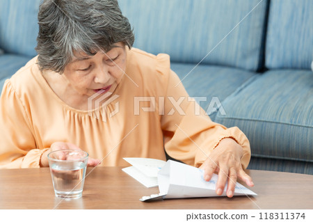 senior woman taking medicine 118311374