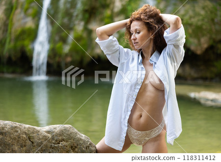 Portrait of half-naked woman in white shirt and white panties against the background of tropical waterfall 118311412