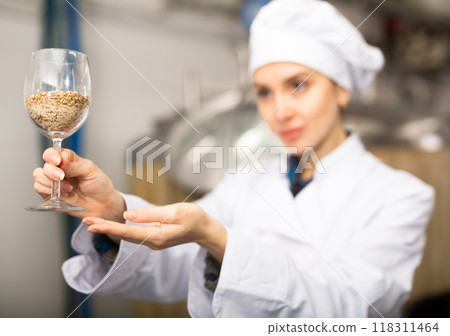 Female brewmaster holding glass of malt 118311464