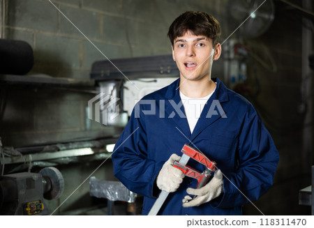 Young guy posing with vice in workshop Young guy posing with vice in workshop 118311470