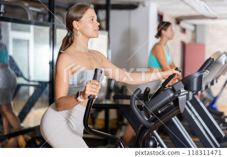 Young woman working out on elliptical machine Young woman working out on elliptical machine 118311471
