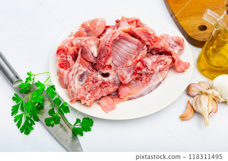 Plate with pieces of fresh raw rabbit, greens and condiments on table Plate with pieces of fresh raw rabbit, greens and condiments on table 118311495