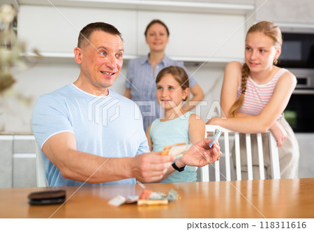 Father gives pocket money to children and wife in kitchen 118311616
