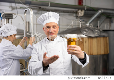 Happy brewery owner inviting to tasting amber beer 118311623