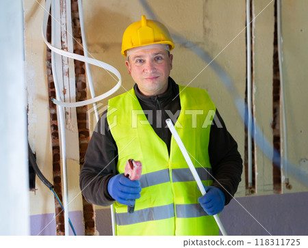 Electrician with cable duct in hands looking at camera Electrician with cable duct in hands looking at camera 118311725