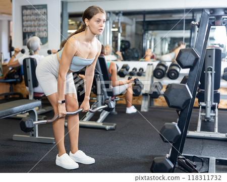 Young woman lifting barbell in gym 118311732
