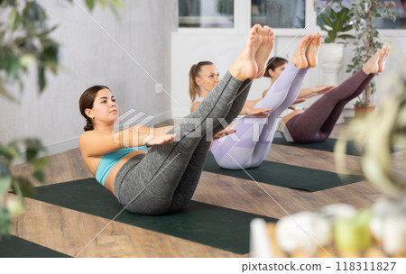 Young girl doing Havasana asana during group yoga workout 118311827