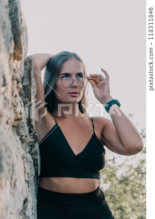 Woman Glasses Rock Portrait of a young woman wearing glasses and standing by a rock. 118311846