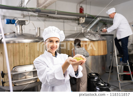 Portrait of woman brewmaster holding bunch of hops pellets Portrait of woman brewmaster holding bunch of hops pellets 118311857