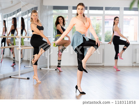 Confident woman leading group heels dance class in studio 118311858