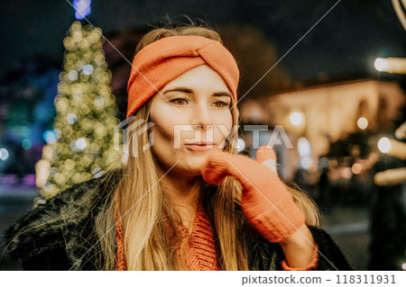happy smiling woman in a red hat stands on the street, holding light in her hands. Winter fun on the street: Christmas or New Year celebration. Slow motion 118311931