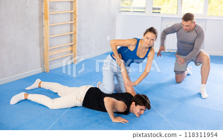 Guy and woman train of performing protection with wring hands during training in self-defense Guy and woman train of performing protection with wring hands during training in self-defense 118311954