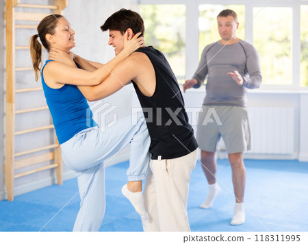 Guy and woman train to perform defense of strangling opponent, while learning self-defense 118311995