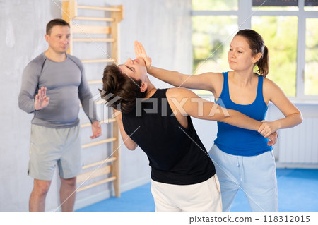 Woman practices blows to head of her attacking man during self-defense training under the guidance of trainer Woman practices blows to head of her attacking man during self-defense training under the guidance of trainer 118312015