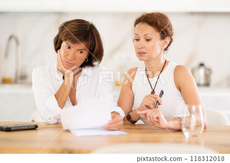 Two woman at table and trying to figure out finance problem and thinking about bills at home 118312018