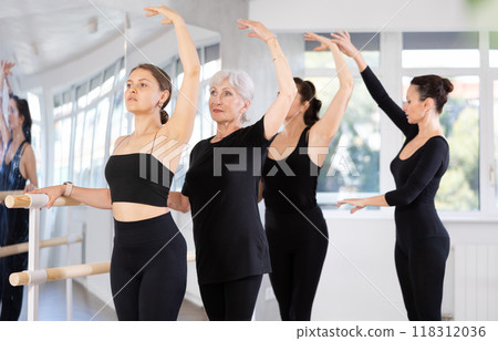 Teacher conducts class with girls in ballet studio, observes doing third position exercise. Teacher conducts class with girls in ballet studio, observes doing third position exercise. 118312036