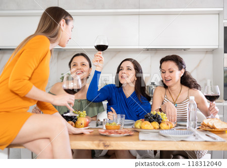 During gathering with friends, woman sit on table, enjoying food and wine, chatting, talking 118312040