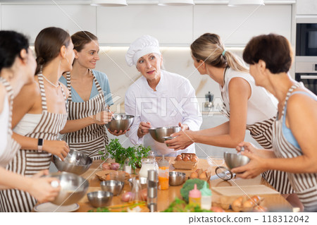 Mature female cook holding bowl and whisk 118312042