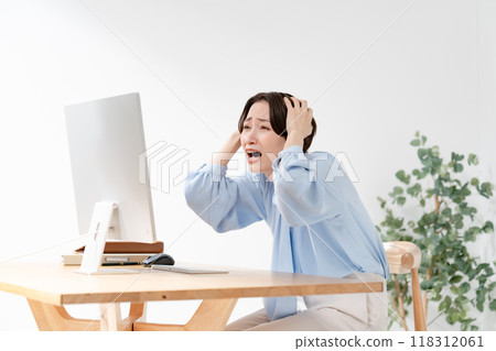A woman holding her head looking at a computer 118312061
