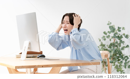 A woman holding her head looking at a computer A woman holding her head looking at a computer 118312064
