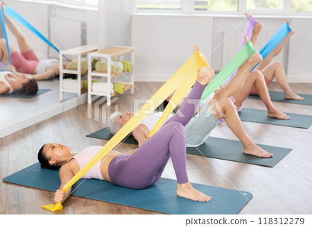 Asian woman exercising with elastic band at group training Asian woman exercising with elastic band at group training 118312279
